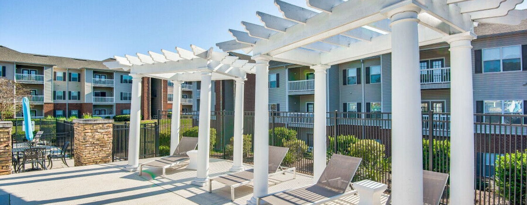 a patio with a bench and a fence in front of a building